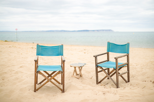 Directors chairs on a beach on Dorset Coast. UK summer seaside scene with sea and the Isle of Wight in the background