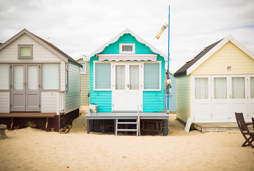 Row of colorful painted wooden beach huts on a sandy beach. Hengistbury Head, Dorset, UK