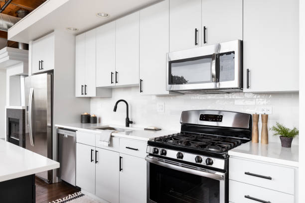 uma cozinha branca com eletrodomésticos de aço inoxidável. - indoors contemporary domestic room sparse - fotografias e filmes do acervo