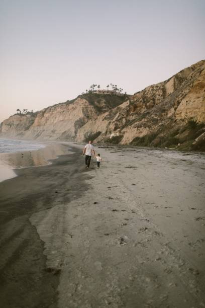 istock Father and son walking down the beach in the distance 1454675901