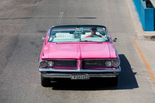 Havana, Сuba - April 21, 2018: Classic American car, 1962 Pontiac Bonneville Convertible, used to carry tourists around the city, driving down a street in Havana, Cuba, elevated view.
