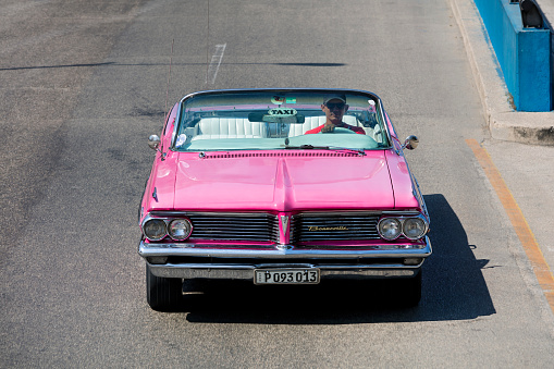 Havana, Сuba - April 21, 2018: Classic American car, 1962 Pontiac Bonneville Convertible, used to carry tourists around the city, driving down a street in Havana, Cuba, elevated view.