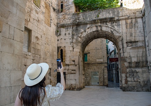 A young woman taking photos of the golden gates of Diocletian's Palace in Split, Croatia