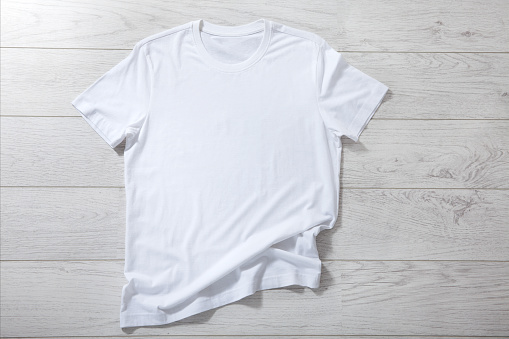 White shirt mockup isolated - pleated, wrinkled t-shirt on white background top view closeup