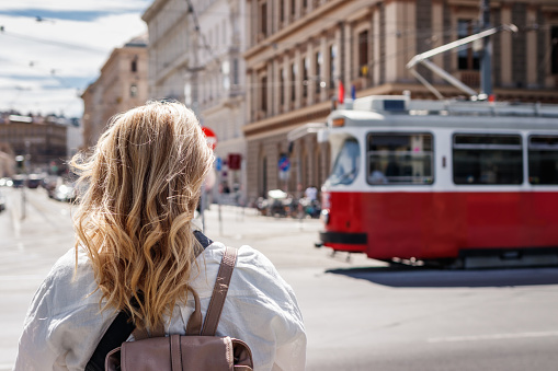 Woman tourist looking at passing tram in Vienna. Tramway public transportation