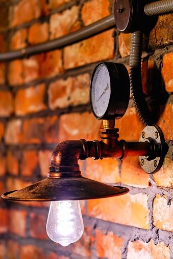 A steampunk style interior design close up lamp and manometer over red brick wall background