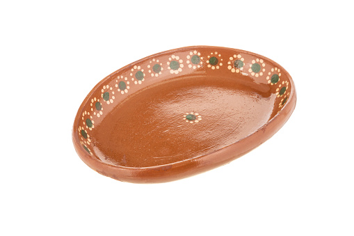 Oval red clay plate made in Mexico. Traditional handmade Mexican clay crockery. isolated White background.