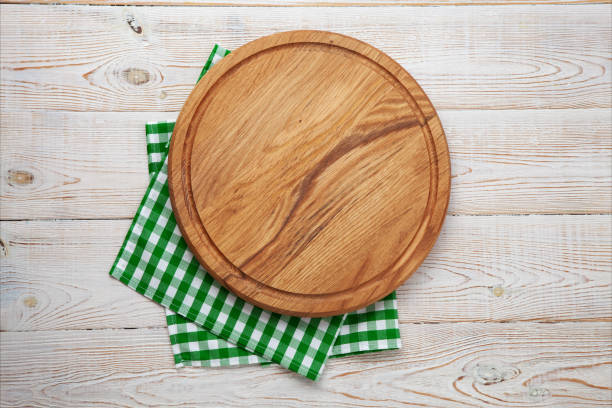istock Empty pizza board and napkin on white wooden top view. 1454681481