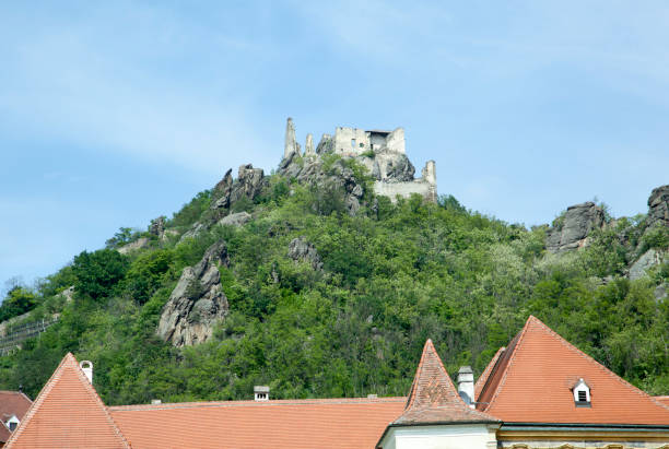 The view through Durnstein town red rooftops of the castle old ruins on a hill (Austria).