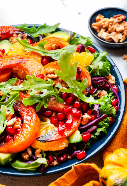 istock Fresh pumpkin salad with red cabbage, avocado, lettuce, arugula, pomegranate and nuts. Vegan healthy eating, slow comfort food. White table background. Top view 1454688462