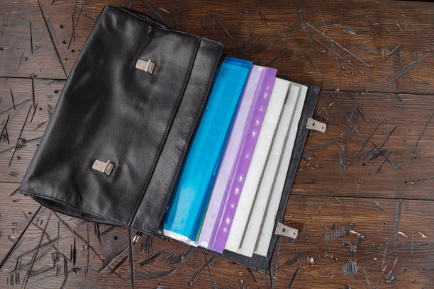 Leather briefcase with documents. Lots of documents in the portfolio. Various documents on the table. Business briefcase. View from above.