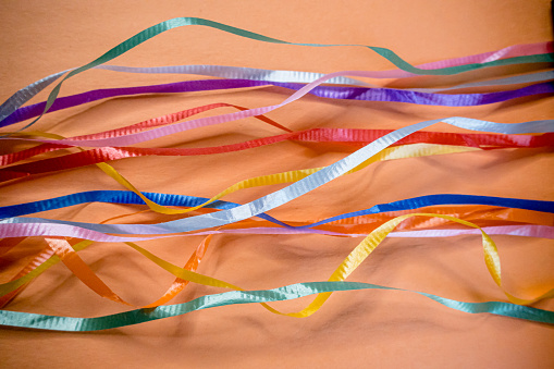 Loose ribbons are aranged on colourful paper for an abstract fusion of colours.