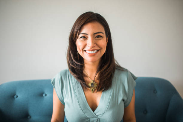 portrait of a smiling latin woman looking at the camera sitting on the sofa at home - 36 imagens e fotografias de stock