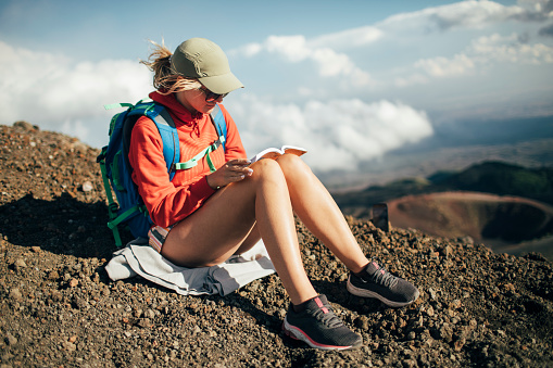 Hiker woman reading book on sloops of Mt Etna, Sicily.