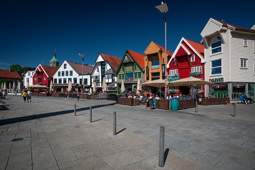 Harbour and pier of Stavanger with colorful timber houses in Norway, people sitting in bars, during sunshine and blue sky