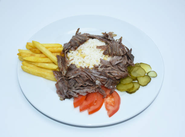 istock Iskender doner kebab with rice, fried potatoes, tomatoes and pickled cucumbers served on a white plate. Isolated. Meat doner menu, iskender menu, turkish special meat doner. 1454704477