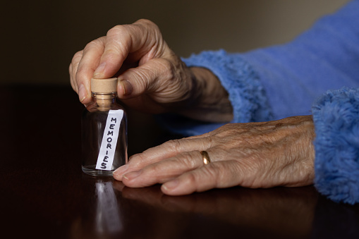 Mensaje dentro de una botella de vidrio con la palabra recuerdos. Se sostiene de la mano de una anciana que quiere recordar. Concepto de pedir un deseo y nostalgia por el pasado. photo