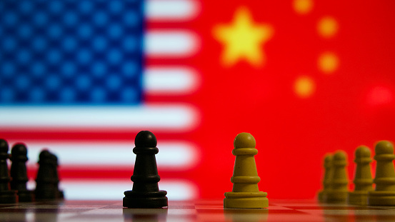 Pawn chess pieces facing each other on a chess board representing potential economic and political conflicts between the United States of America and China.