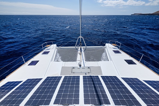 A part of a solar panel on the dock of a sailboat on a sunny day