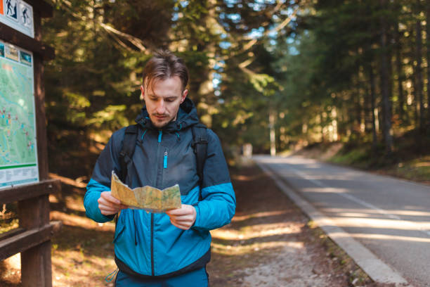 istock Young male hiker lost in the woods holding a map 1454708538