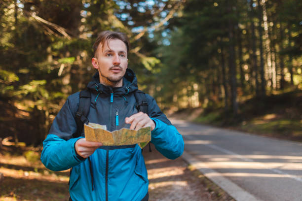 istock Young male hiker lost in the woods holding a map 1454708546