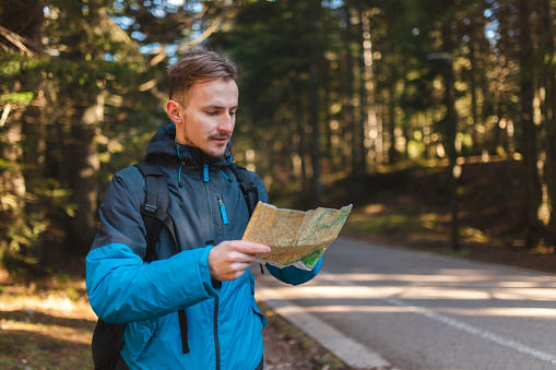 Young male hiker lost in the woods. He is holding a map.