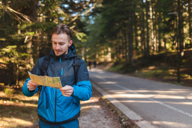 istock Handsome young hiker looking at the map outdoors in the forest 1454708558