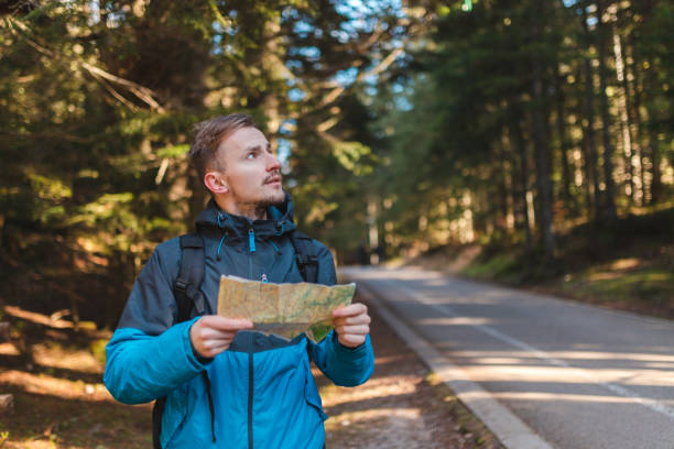 istock Handsome young hiker looking at the map outdoors in the forest 1454708560