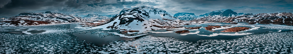 Snowy landscape of Hardangervidda national park with mountains and icy lakes in Norway, from above
