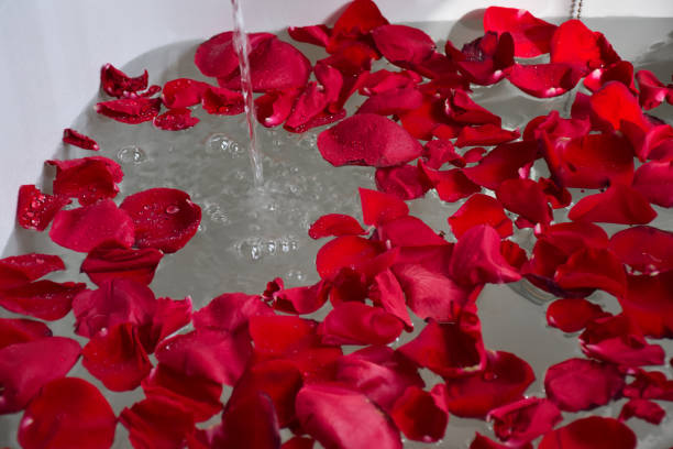 Closeup bathtub with red rose petals filling up with water