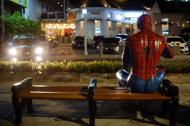 A statue of the superhero Spiderman who appears to be sitting alone in a city park at night Yogyakarta, Indonesia, Feb 16, 2019. A statue of the superhero Spiderman by Amboro Liring who appears to be sitting alone in a city park at night. super film title stock pictures, royalty-free photos & images