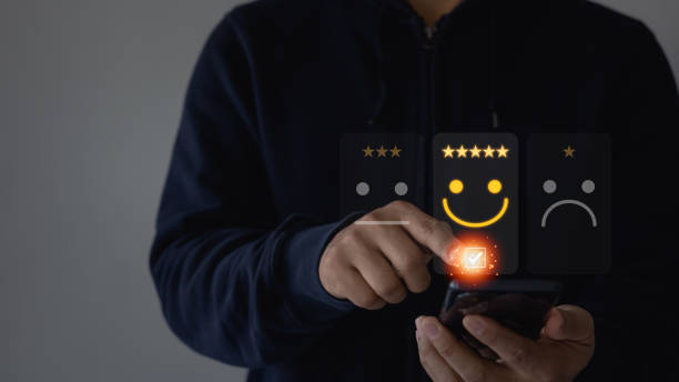 Business person using mobile smartphone for select smiley face icon for client evaluation and customer satisfaction after use product and service concept. Online satisfaction service survey.