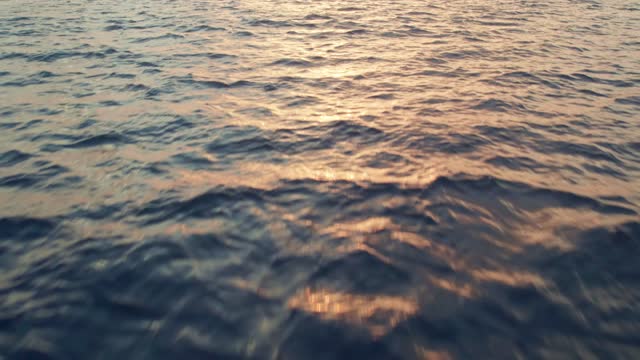 Very fast flying over the surface of the sea. Following the reflect of the sun. Sunrise at sea. Sunset at sea. The dolly shot and tilt up with focus on the sun. Version 4c