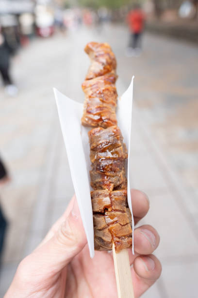 istock Grilled Mochi Cake skewer in hand 1454715931