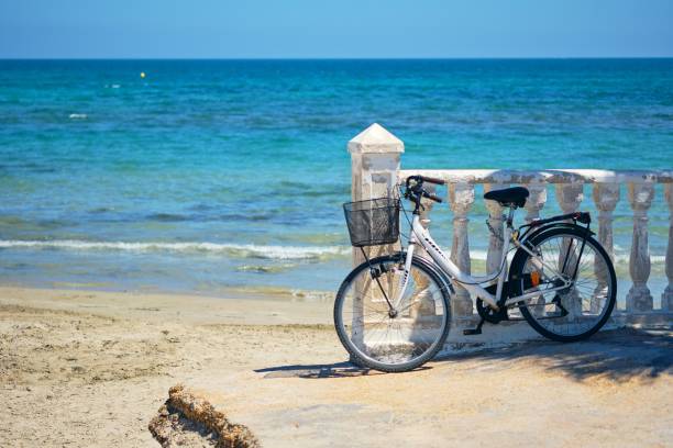 istock Vintage bicycle leaned to white balustrade railings against a turquoise seascape 1454716570