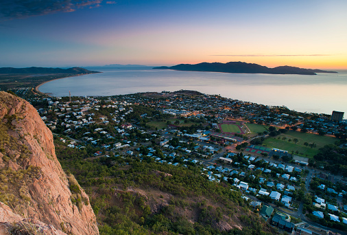 Aerial view from a mountain lookout of Townsville, Queensland Australia at sunset looking towards the distant horizon with colorful sky and Magnetic Island