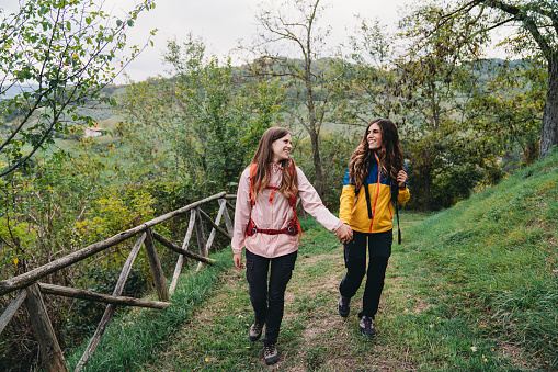 A young adult couple is walking together in the nature. They are hiking together.