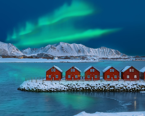 Amazing scenery wit traditional red wooden houses on the shore of Offersoystraumen fjord with Northern Lights. Location: Vestvagoy island, Lofoten; Norway, Europe