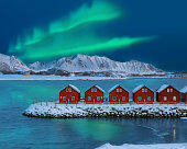 Amazing scenery wit traditional red wooden houses on the shore of Offersoystraumen fjord with Northern Lights