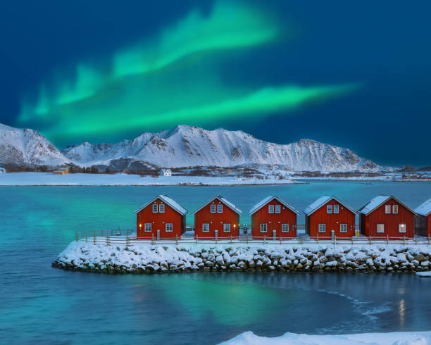 amazing scenery wit traditional red wooden houses on the shore of offersoystraumen fjord with northern lights - lofoten imagens e fotografias de stock