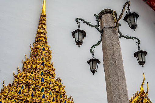 A steeple of Wat Po and French street light from outside the temple.