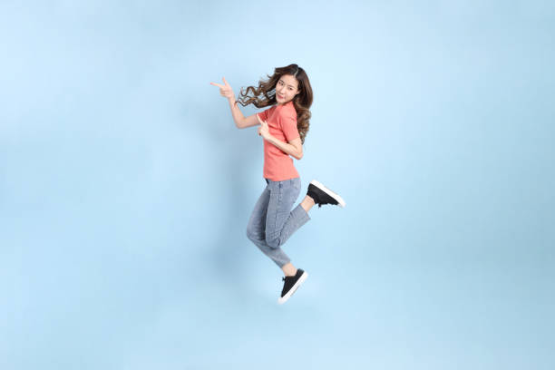 The young adult Asian woman with casual clothes with jeans standing on the blue background.