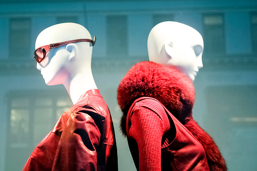 Fashionable woman mannequins in store window through the glass in New York City wearing red.