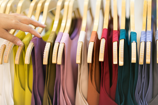 Clothes that are arranged on shelves and hangers.