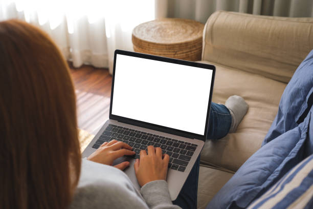 istock Mockup image of a woman working and typing on laptop computer with blank screen on sofa at home 1454737117