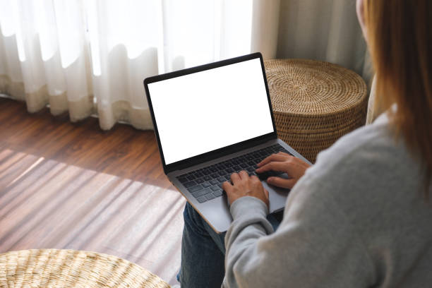 istock Mockup image of a woman working and typing on laptop computer with blank screen while sitting on a sofa at home 1454737119