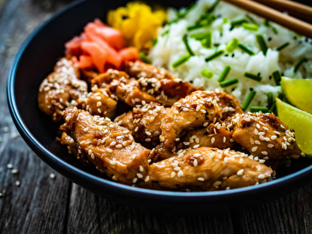 istock Stir-fried chicken meat, white rice and vegetables on wooden table 1454737307