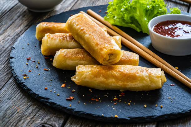 istock Spring rolls filled with meat and vegetables served with soy sauce on wooden table 1454739587