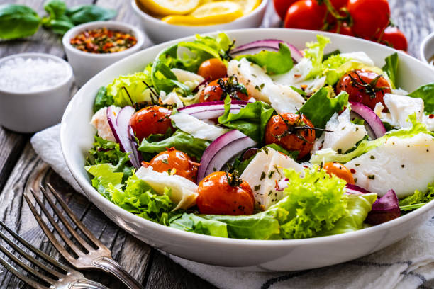 istock Roast fish and vegetable salad  on wooden background 1454741398