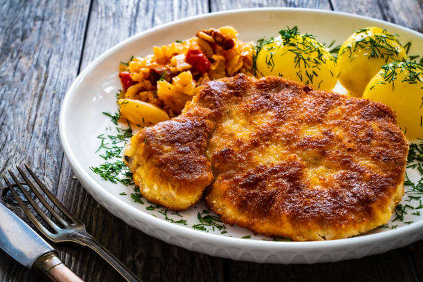 côtelette de porc frit panée avec pommes de terre bouillies et chou cuit sur table en bois - wiener schnitzel photos et images de collection